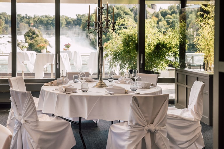 Elegantes Esszimmer mit Blick auf Wasserfall und Bäume.