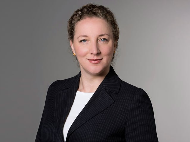 Frau in Anzug vor grauem Hintergrund.