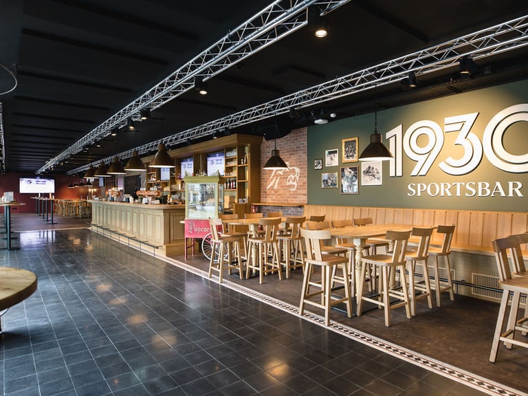 Innenansicht einer Sportbar mit Tischen und Theke.