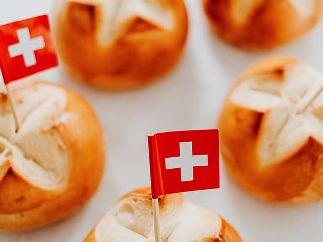 Schweizer Brötchen mit Fahnen auf Tisch.