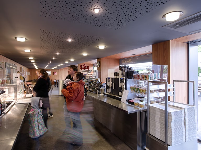 Innenansicht einer Cafeteria mit Kunden an der Theke.",