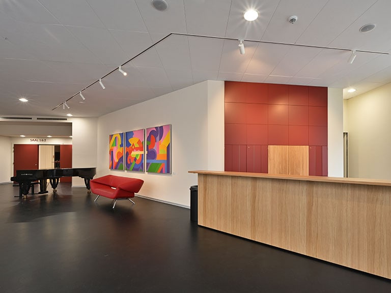 Moderne Lobby mit rotem Sofa, Holztheke und bunter Kunst an der Wand.