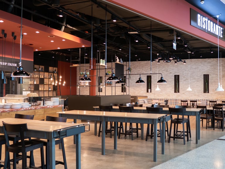 Leeres Restaurant mit Holz- und Metallmöbeln, hängende Leuchten.