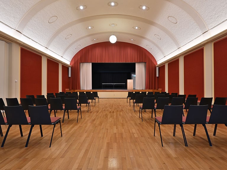 Leerer Saal mit Holzfussboden und Bühne.