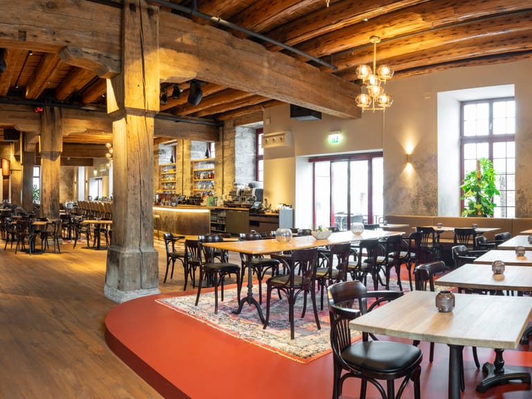 Grosses, gemütliches Restaurant mit Holzbalkendecke und vielen Tischen.