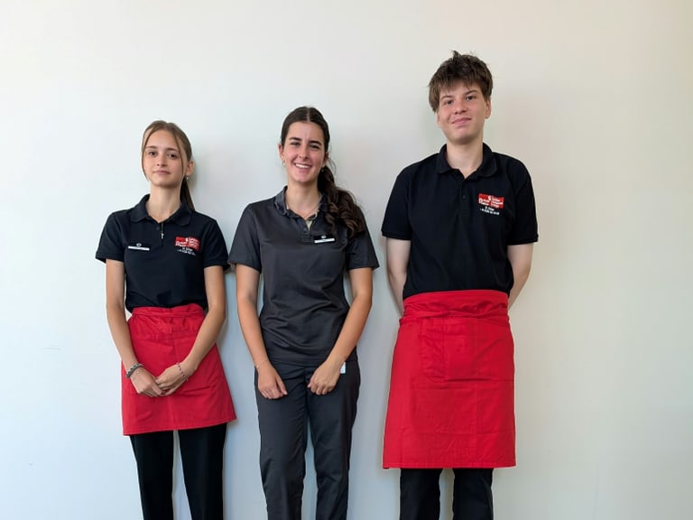 Drei Personen in Arbeitskleidung vor einer weissen Wand.