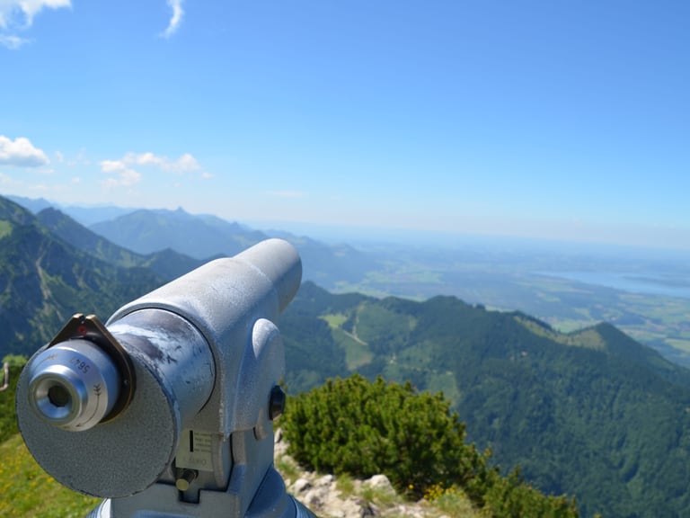 Silbernes Fernrohr mit Bergblick und blauem Himmel.