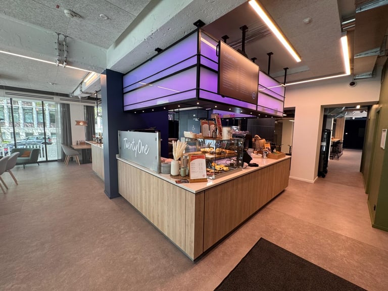 Moderne Cafeteria mit Theke und Beleuchtung.