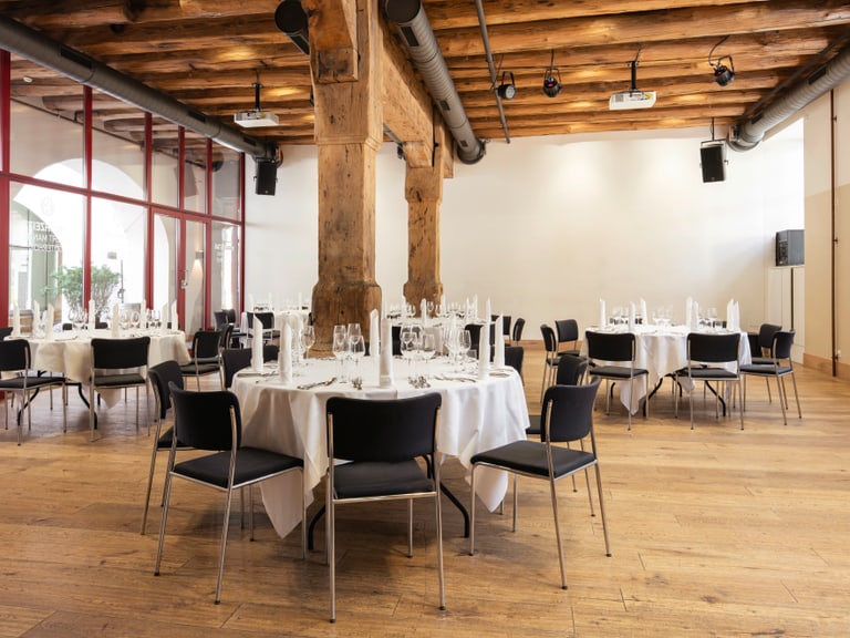 Runder Tisch im rustikalen Veranstaltungsraum eingedeckt.