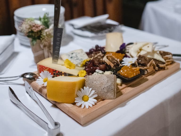 Käseplatte mit verschiedenen Käsesorten und Blumen auf Tisch im Restaurant.