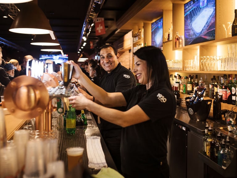 Barkeeper serviert Getränke in einer belebten Bar.