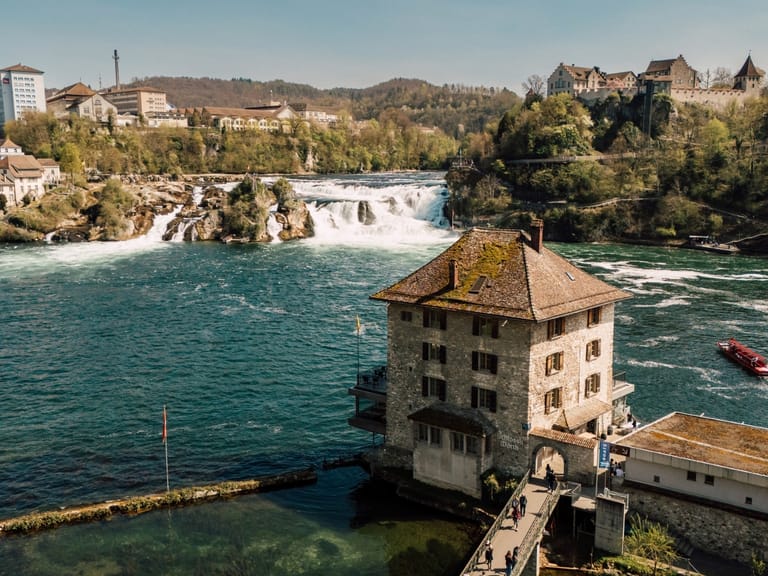 Luftbild der Rheinfall-Wasserfälle und umliegende Gebäude bei Sonnenschein.