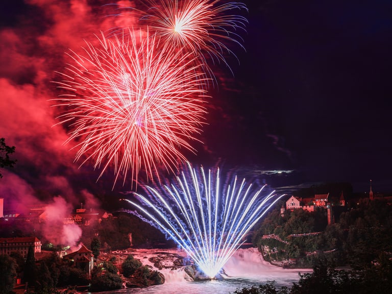 Feuerwerk über dem Rheinfall bei Nacht.