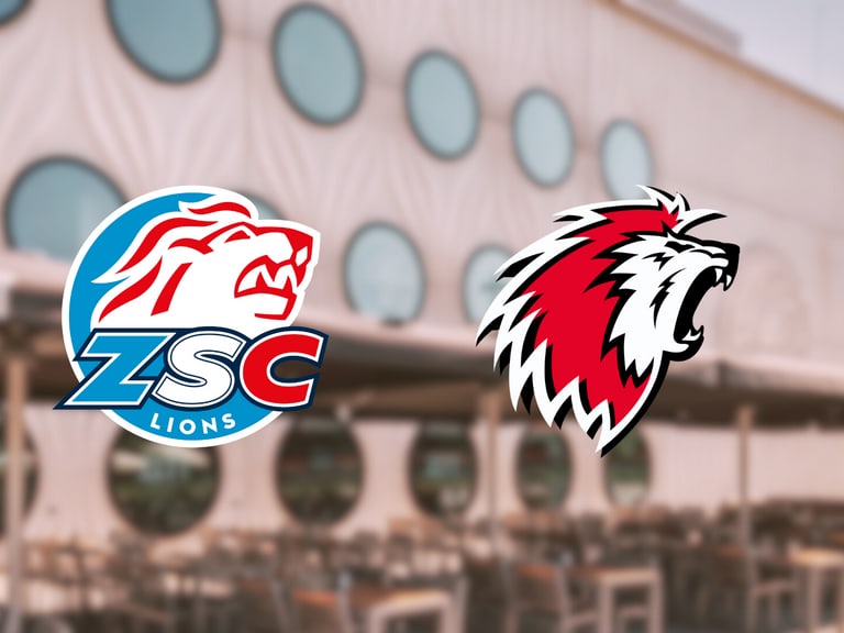 Zwei Löwenlogos vor Gebäude mit runden Fenstern.