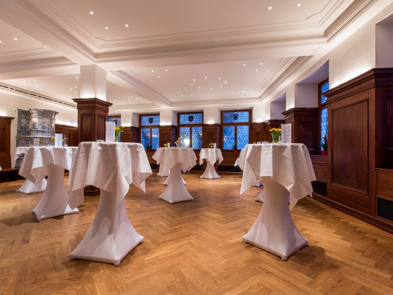 Eleganter Raum mit Stehtischen und Holzverkleidung.