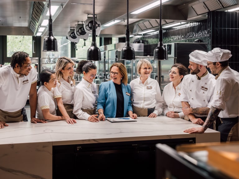Gruppe von Köchen und einer Managerin in einer Restaurantküche.