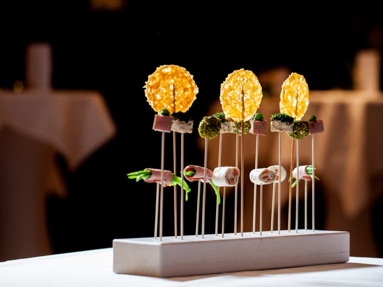 Gourmet-Appetizer auf Holzspiessen arrangiert auf einem Tisch.