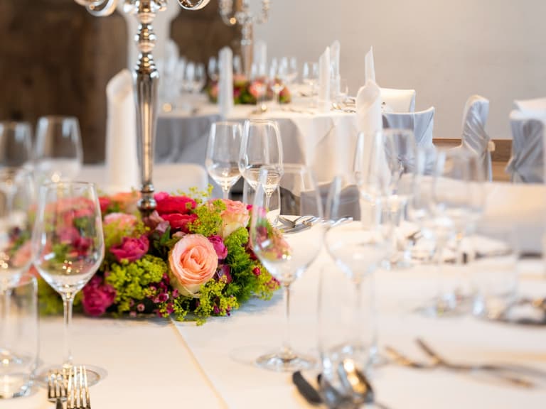 Elegant gedeckter Tisch mit Blumendekorationen und Kerzenhalter.