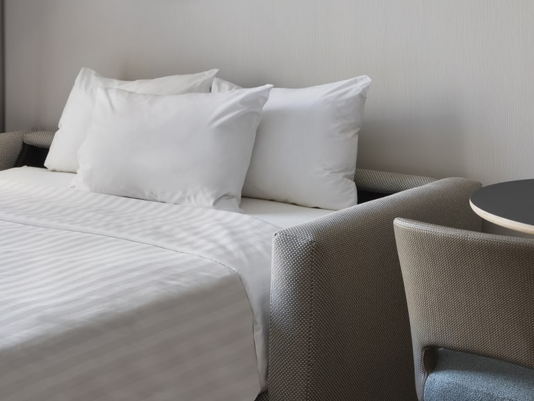 Zimmer mit Doppelbett und Tisch mit zwei Stühlen.