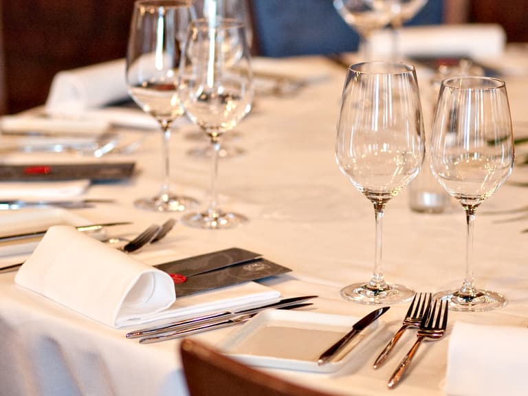 Eleganter Tisch mit Weingläsern und Besteck gedeckt.
