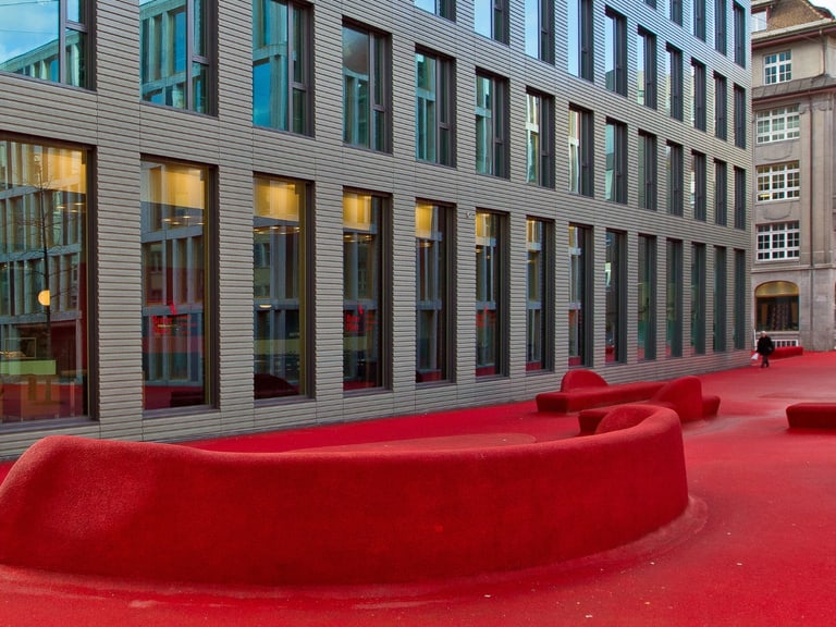 Moderne Gebäude mit rotem gepflastertem Platz davor.