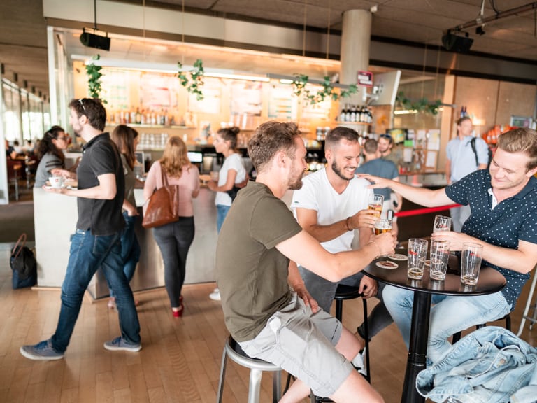 Menschen geniessen Getränke in einer belebten Bar.