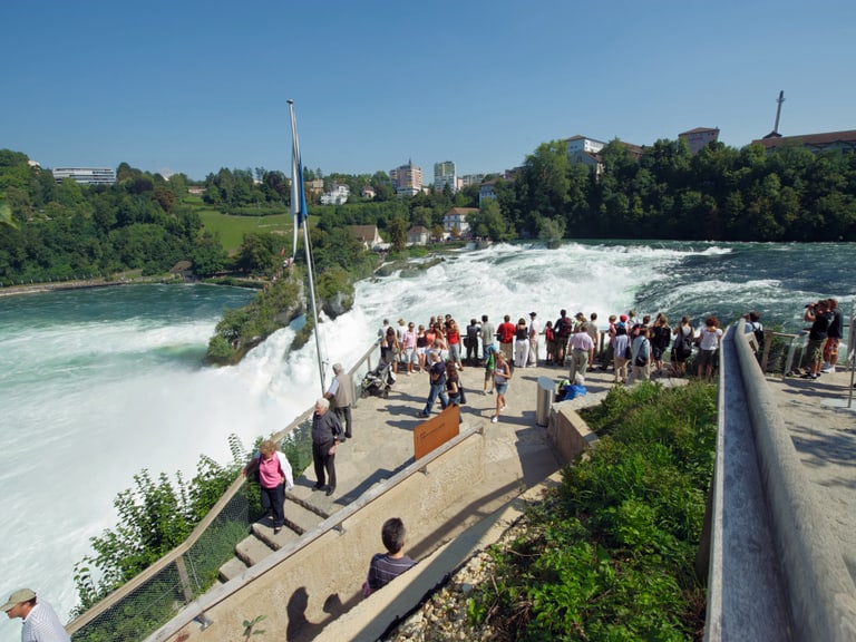 Menschenmenge betrachtet Rheinfall bei Sonnenschein.