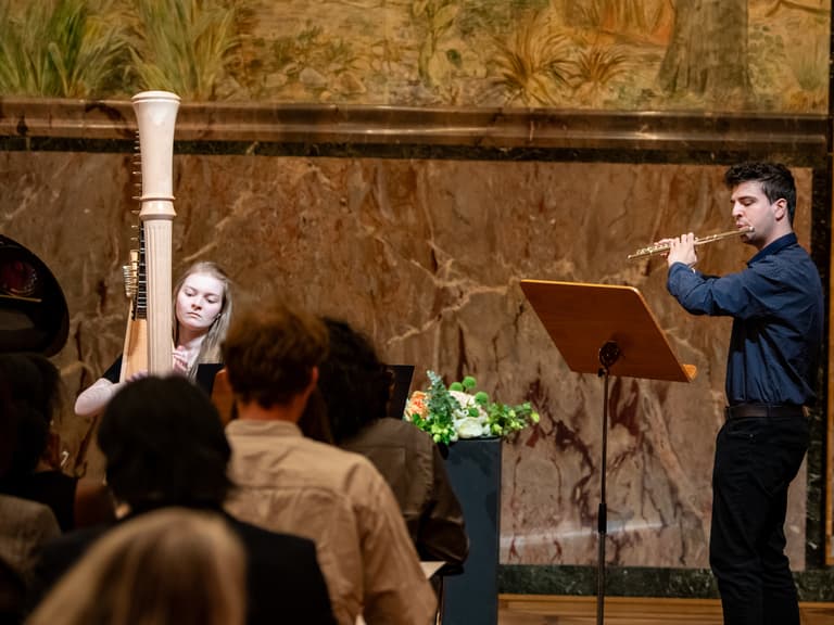 Harfenspielerin und Flötist bei Konzertauftritt vor Publikum.