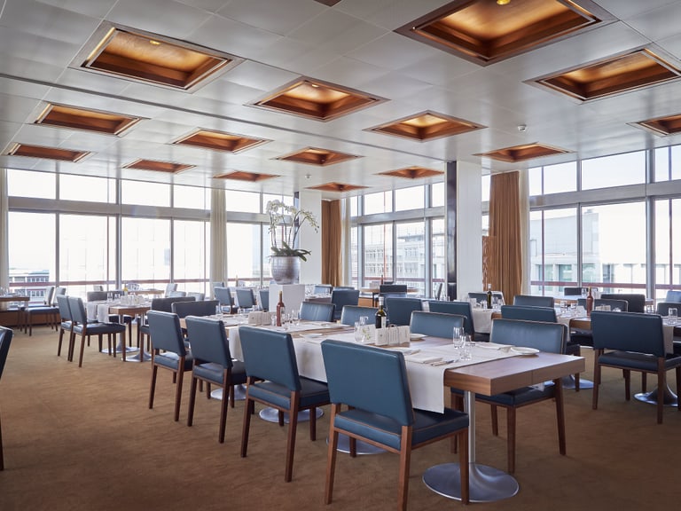 Modernes Restaurant mit gedeckten Tischen und Panoramafenstern.