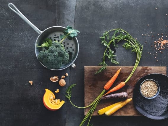 Gemüse mit Topf, Schneidebrett und Schalen auf dunklem Hintergrund.