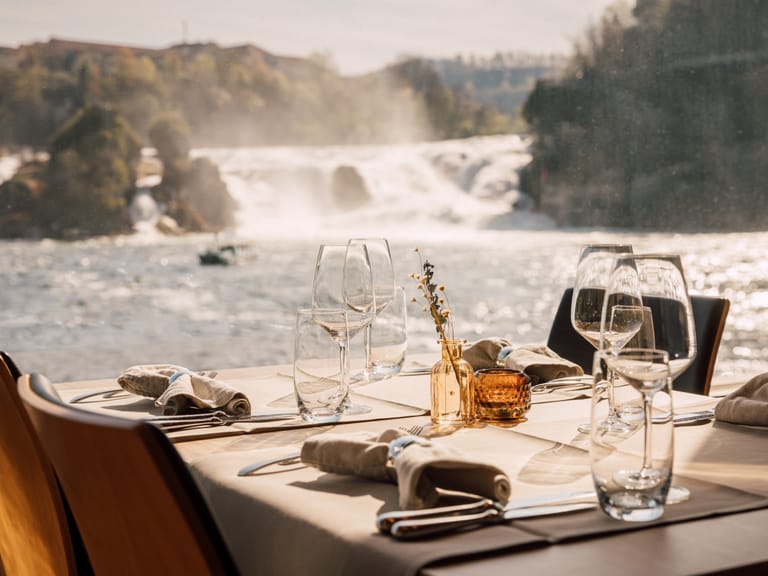 Gedeckter Tisch mit Wasserfall im Hintergrund.