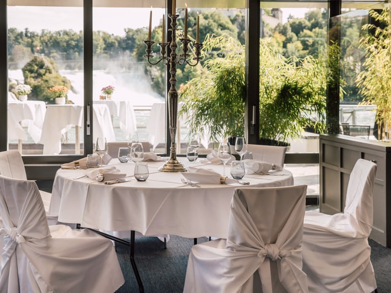 Elegantes Esszimmer mit Blick auf Wasserfall und Bäume.