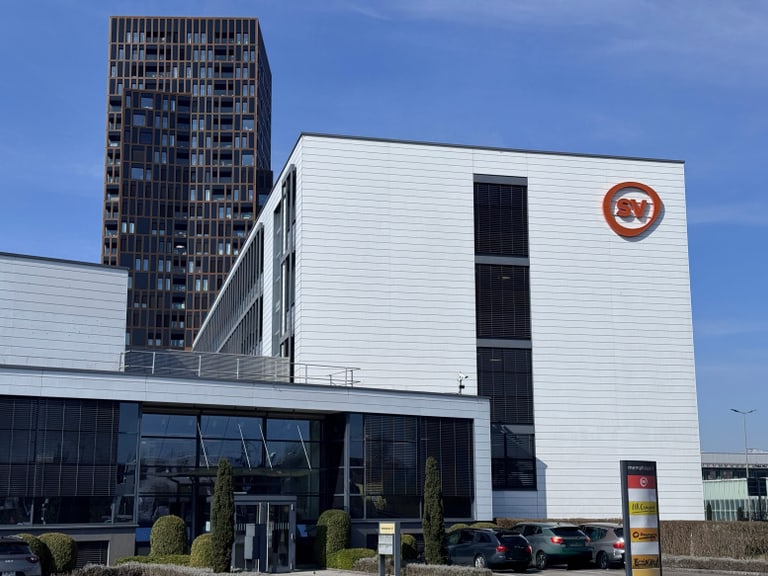 Modernes Gebäude mit Firmenlogo bei sonnigem Himmel.