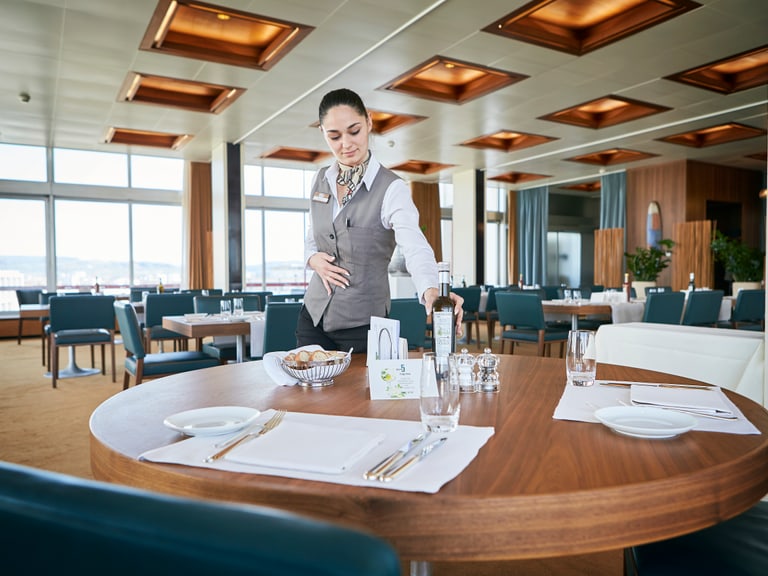 Kellnerin deckt Tisch in elegantem Restaurant ein.