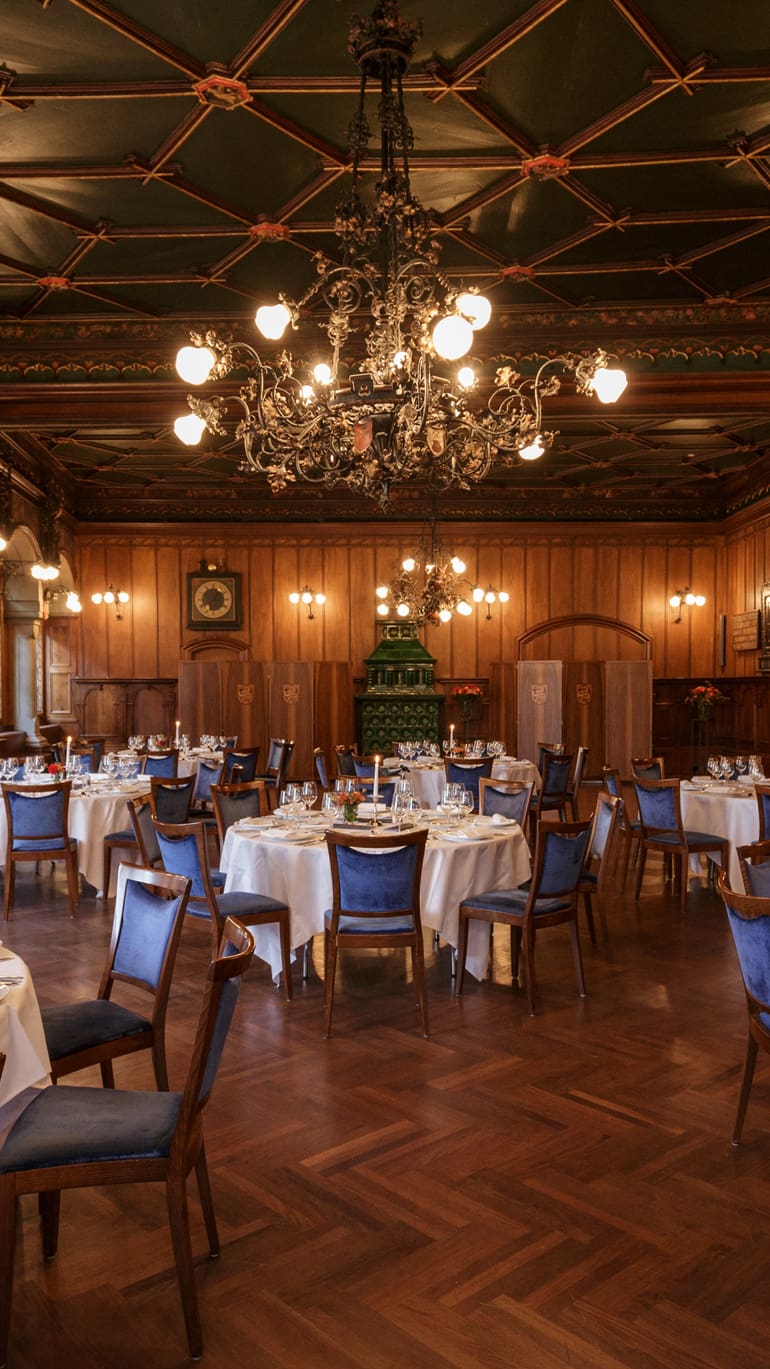 Eleganter Speisesaal mit runden, eingedeckten Tischen und Kronleuchtern.