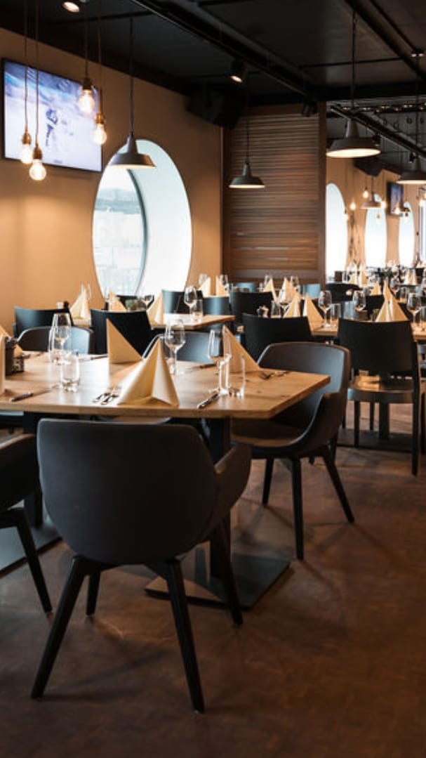 Modernes Restaurant mit runden Fenstern und elegant gedeckten Tischen.