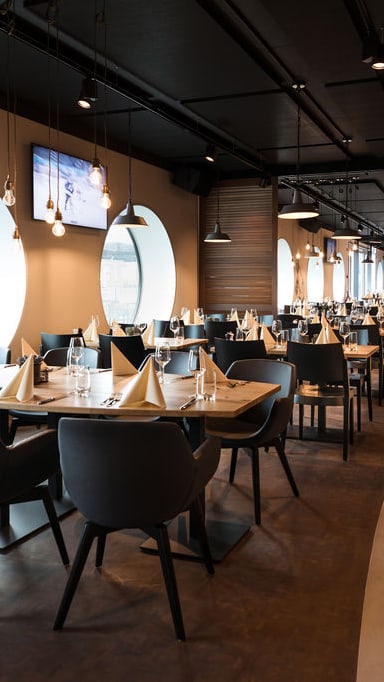 Restaurant mit gedeckten Tischen, Fenster mit Sportdekorationen.