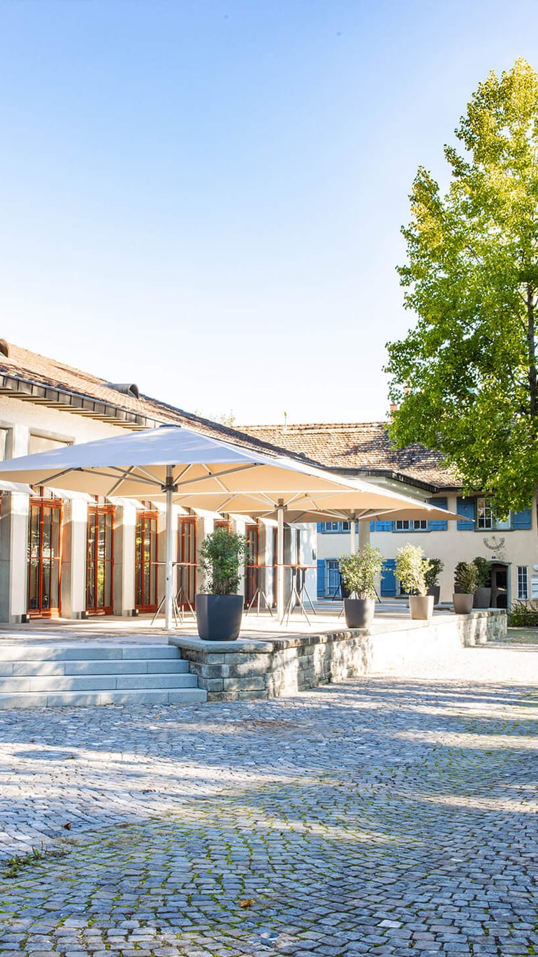 Person walking past a sunny building with a terrace.